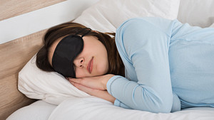 Woman sleeping on her side with an eye mask.