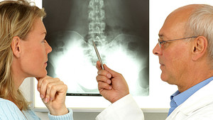 Doctors examining x-rays of patient&#039;s spine.