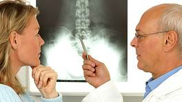 Doctors examining x-rays of patient&#039;s spine.