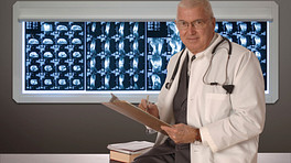 Doctor standing in front of a board of CT scans.