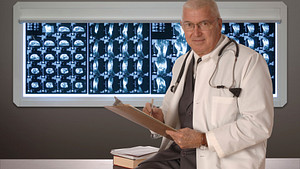 Doctor standing in front of a board of CT scans.