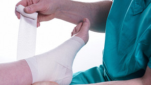 Nurse taping a patient&#039;s foot and ankle.
