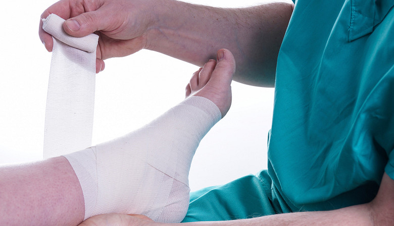 Practitioner taping an ankle injury