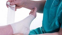 Nurse taping a patient&#039;s foot and ankle.