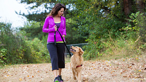 Woman walking her dog outdoors.