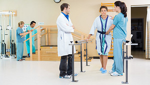 Physical therapist working with a patient to walk.