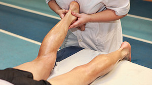 Therapist doing myofascial release therapy on a man&#039;s ankle