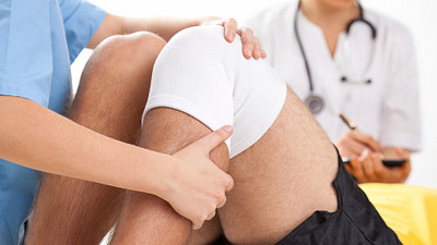 Physical therapist stretching a patients knee.