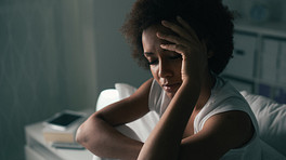 Woman sitting on bed suffering from insomnia and depression