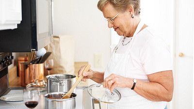 Woman with and apron stirring food in a pot on the stove