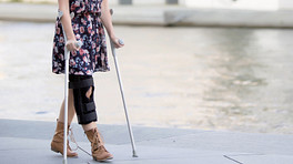女人膝盖撑使用拐杖。