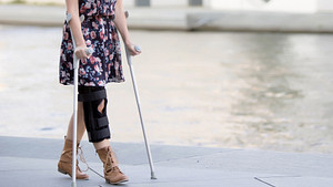 Woman with a knee brace using crutches.