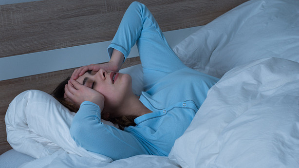 Woman lying awake with her hands on her head in frustration