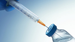 Syringe injected into a bottle of medicine.