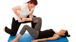 Therapist assisting patient with lower back stretches.