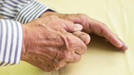 Elderly main massaging his hands in pain.