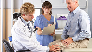 Physician consulting an older patient about knee pain