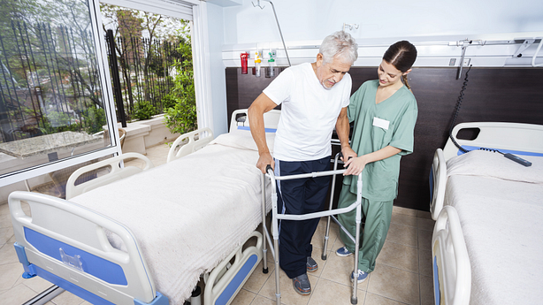 Therapist assisting a patient to help him walk after surgery.