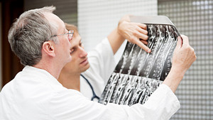 Two male physicians reviewing a series of x-rays