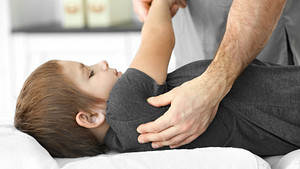 Physical therapist stretching a child&#039;s upper back