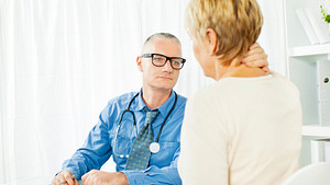 Woman with neck pain speaking to a doctor