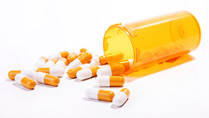 Prescription bottle and pills spilled on table