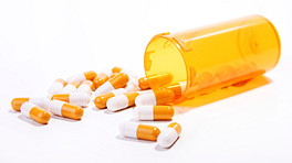 Prescription bottle and pills spilled on table