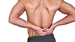 Posterior view of a male&#039;s back as he grabs his lower back with pain.