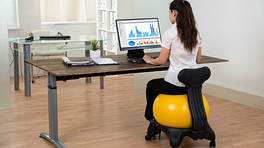 Woman sitting on a ball chair at a desk working