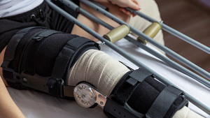 Knee wrapped in a bandage with a brace and crutches.