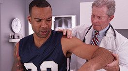 医生正在检查一名运动员的肩部疼痛。