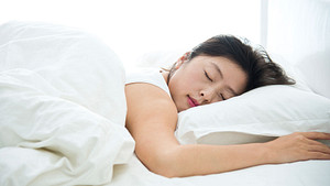 Woman sleeping on her stomach in a bed