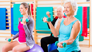 Seniors and instructor in an exercise class doing exercise ball exercises with hand weights