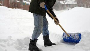 Lower body of a person shoveling snow
