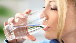 Woman drinking from a water glass.