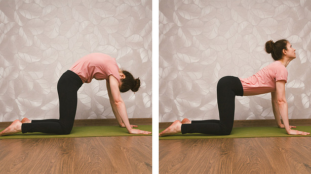 Woman performing cow-cat pose yoga stretch on a yoga mat.