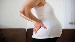 Profile view of a pregnant woman with back pain