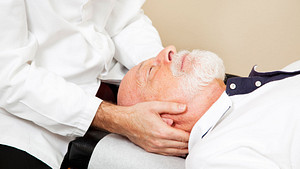 Chiropractor adjusting an older man&#039;s neck