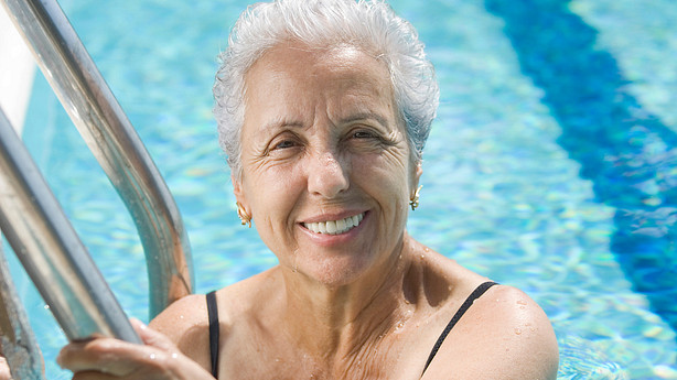 Older woman smiling and standing in a swimming pool