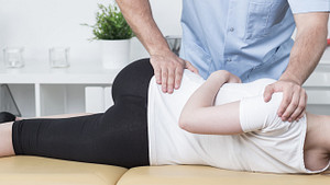 Practitioner manipulating a patient&#039;s lower back.