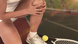 Tennis player grabbing knee in pain.