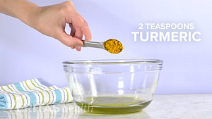 2 teaspoons of turmeric being poured into a bowl.