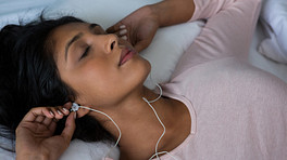 Woman putting in ear buds as she relaxes.