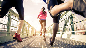 Group of runners running across a walking bridge.