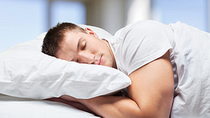 Young man sleeping in a bed with a pillow