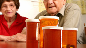 Elderly couple overlooking a collection of pill bottles.