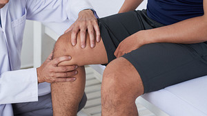 Physician examining an older patient&#039;s knee