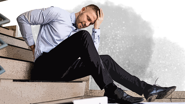 A man sitting on stairs with his hand on his back.