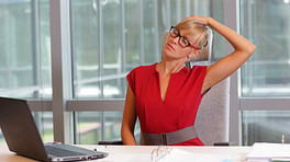 Woman performing a neck exercise at her desk
