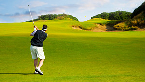 Man driving a golf ball on the golf course.